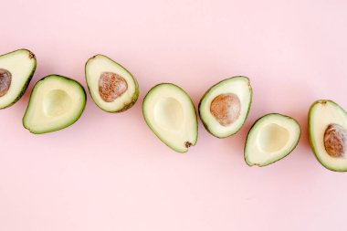 Pembe arka planda avokado. Avokadolu tropik soyut bir arka plan. Yemek konsepti. düz yatış, üst görünüm