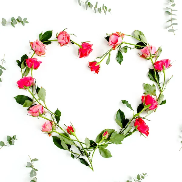 The heart is lined with red roses on white background. Valentines background. Floral pattern. Flat lay, top view.