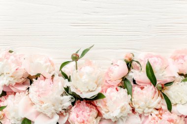 Çiçek çerçeveli çelenk pembe ve bej şakayık çiçekleri çiçek tomurcukları, okaliptüs dalları ve beyaz ahşap arka planda izole edilmiş yapraklar. Düz yatış, üst görünüm