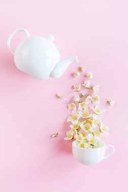 Çaydanlığın yaratıcı düzeni ve pembe arka planda yasemin çiçekleri olan çay fincanı. Yasemin çayı..