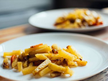 Otlar ve baharatlar baharatlı kızarmış patatesle beyaz tabak içinde servis. Sığ derinliği alan fotoğraf