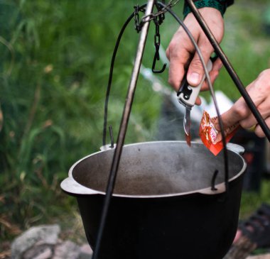 Bir adam bir yemek kampanya hazırlar. Domates çorbası bir açık ateş üzerinde bir tencerede pişirilir