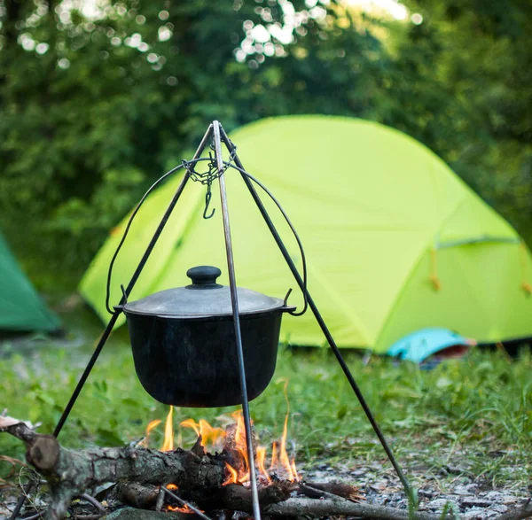 Hiking pot in the bonfire. Traveling in the mountains with tents. Royalty Free Stock Photos