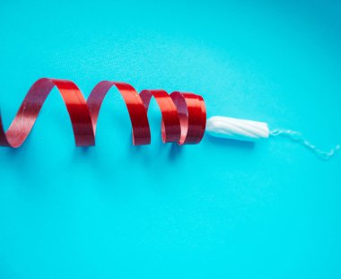 temiz beyaz tampon, menstruasyon kadınsı kavramı. Mavi bir arka plan ve kırmızı kıvırcık şerit üzerinde tampon
