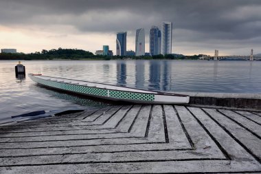 Boş dragon tekne göl tarafı gündoğumu arka plan üzerinde demir attı. Bulutlu gökyüzü ve yansıma yüzeyi