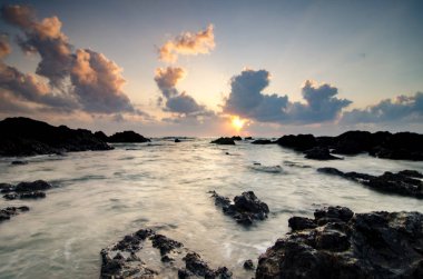 güzel deniz manzaralı ve Pandak Beach Terengganu, Malezya'da bulunan kayaların üzerine akan dalgalar ile gündoğumu sırasında büyülü ışık
