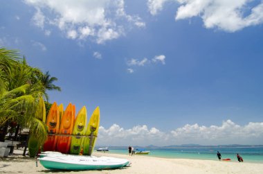 güzel bir plaj sahne, kayaklar yığını üzerinden beyaz kumlu plaj, güneşli bir gün. turistler bulutlu bulutlar ve mavi gökyüzü ile açık deniz suyu üzerinde onların tatil keyfini.