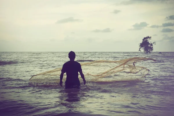 retro görüntü kavramı balıkçı onun balık ağı günbatımı sırasında kumsalda atma