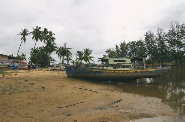 Kumsalda karaya ahşap gemi enkazı. bulutlu gökyüzü ve yeşil ağaç arka plan