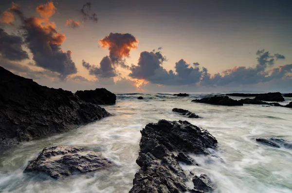 独特の形状の岩の形成と波のしぶき マレーシアのトレンガヌにあるパンダック ビーチで夕日日の出の風景 長時間露光ショットのためにソフト フォーカス ロイヤリティフリーのストック写真