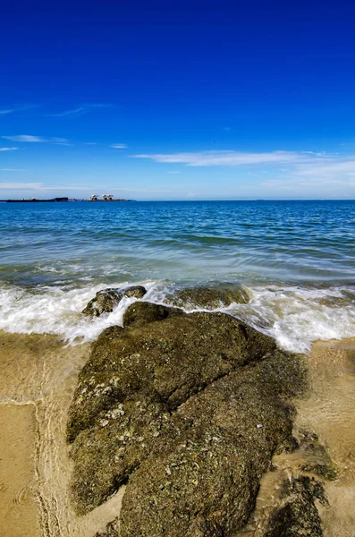 Yumuşak dalga kıyıya, mavi gökyüzü arka plan kayada güneşli gün isabet