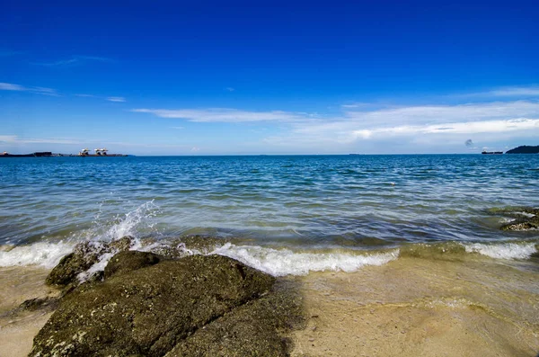 Yumuşak dalga kıyıya, mavi gökyüzü arka plan kayada güneşli gün isabet