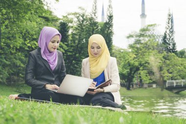 Yaz yeşil park çimenlerin üzerinde oturan ve bir discussion.student ve kentsel lifesyle sahip genç güzel hoş karıştırmak etnik kadın portresi