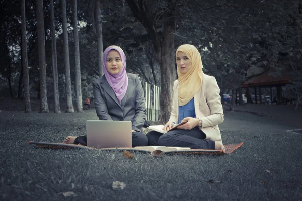 Yaz yeşil park çimenlerin üzerinde oturan ve bir discussion.student ve kentsel lifesyle sahip genç güzel hoş karıştırmak etnik kadın portresi