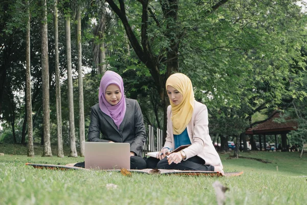 Yaz yeşil park çimenlerin üzerinde oturan ve bir discussion.student ve kentsel lifesyle sahip genç güzel hoş karıştırmak etnik kadın portresi