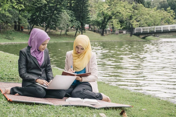 Yaz yeşil park çimenlerin üzerinde oturan ve bir discussion.student ve kentsel lifesyle sahip genç güzel hoş karıştırmak etnik kadın portresi