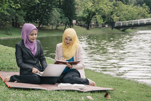 Yaz yeşil park çimenlerin üzerinde oturan ve bir discussion.student ve kentsel lifesyle sahip genç güzel hoş karıştırmak etnik kadın portresi