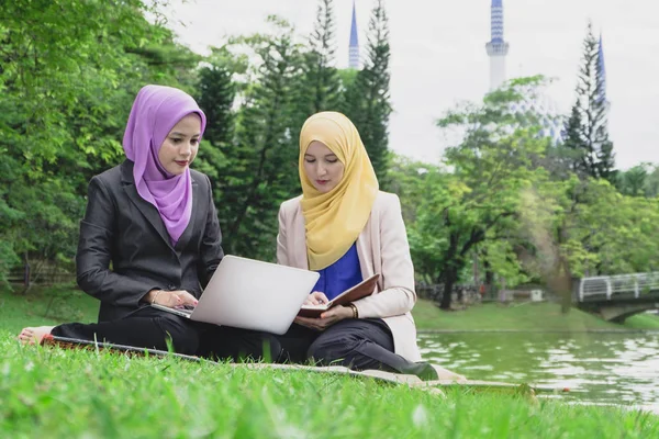 Yaz yeşil park çimenlerin üzerinde oturan ve bir discussion.student ve kentsel lifesyle sahip genç güzel hoş karıştırmak etnik kadın portresi