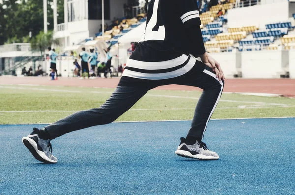 Spor ve sağlıklı yaşam konsepti. germe ve bazı çalıştırmadan önce ısınma sahip genç sporcumuz kırpılmış görüntü