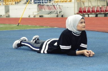 Spor ve sağlıklı yaşam konsepti. çalıştırmadan önce ısınma ve germe hijab ile genç atlet