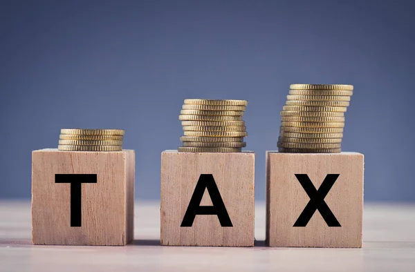 Wood cube with word TAX and stacking coin on wooden table — Stock Photo, Image