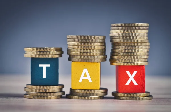 Wood cube with word TAX and stacking coin on wooden table — Stock Photo, Image