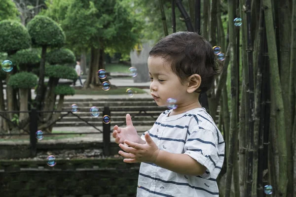 Bambino che gioca con la bolla sotto luminosa giornata di sole al parco pubblico — Foto Stock