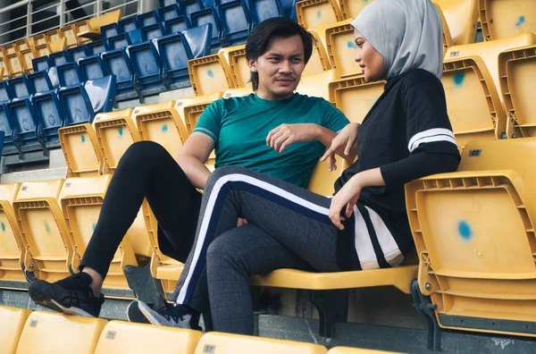 portrait of young sportsman and woman sitting and talking each other
