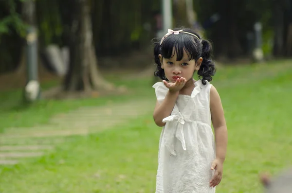 Pouco bonito menina dando voando beijo sobre profundidade rasa de fundo de campo — Fotografia de Stock