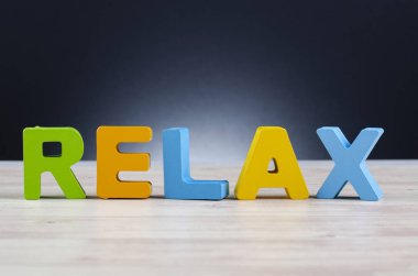alfabe kelime Relax ahşap masa koyu arka plan üzerinde 