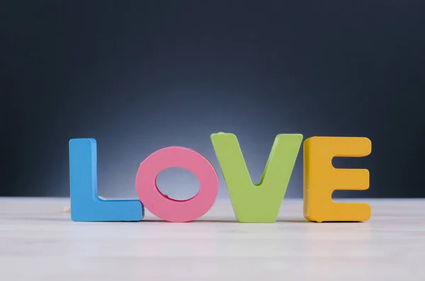 Letras maiúsculas coloridas palavra AMOR na mesa de madeira para o conceito Dia dos Namorados — Fotografia de Stock