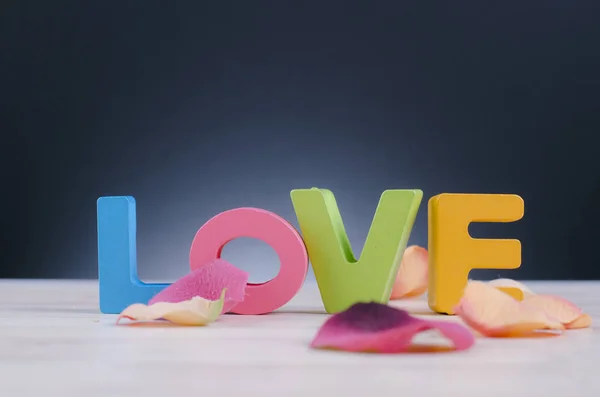 Letras maiúsculas coloridas palavra AMOR na mesa de madeira para o conceito Dia dos Namorados — Fotografia de Stock