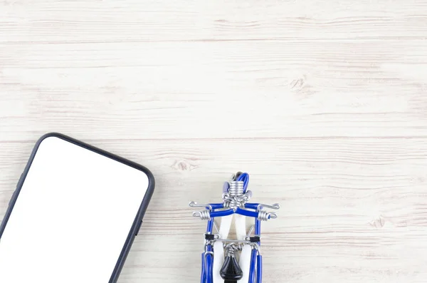Смартфон с белым экраном и миниатюрный скутер на деревянном фоне — стоковое фото