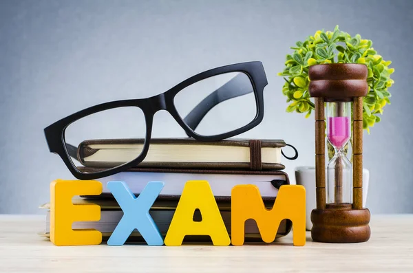 Sınav word kum saati ve gözlük üzerinde yığın kitap — Stok fotoğraf