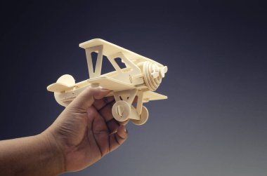 kırpılan el oyuncak ahşap retro uçak seyahat konsepti için koyu renk arka plan üzerinde tutarak