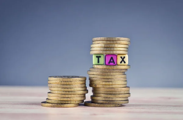 Cubo di legno con la parola TAX e moneta accatastamento sul tavolo di legno — Foto Stock