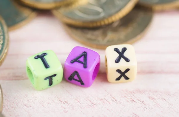 Conceito financeiro, cubo colorido com palavra TAX e empilhamento de moeda — Fotografia de Stock