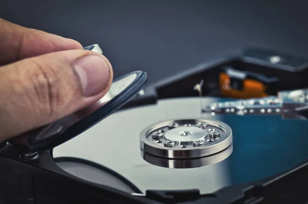 hand holding stethoscope for diagnose old dusty disassembled hard drive from the computer over dark background