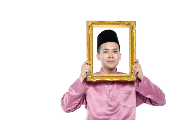 Young and handsome asian man with traditional clothing holding blank frame over white background — Stock Photo, Image