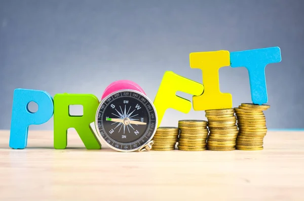 Stacking coins and word PROFIT on wooden desk over beautiful reverberation gradient background — Stock Photo, Image