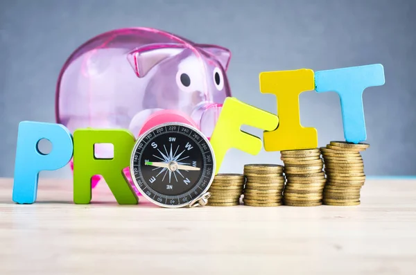 Stacking coins and word PROFIT on wooden desk over beautiful reverberation gradient background — Stock Photo, Image