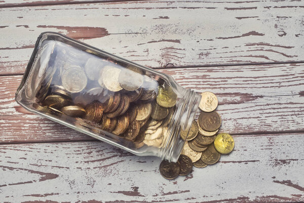 money savings concept , glass jar full with coins. reflection and low light effect