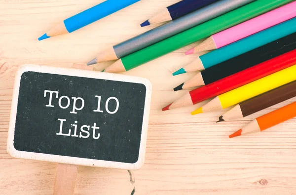 Palavra TOP 10 LISTA escrito em sinalização de madeira sobre lápis colorido na mesa — Fotografia de Stock