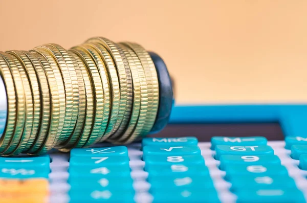 Девальвация и финансовый кризис, калькулятор и монеты, плотно сжатые в G-Clamp — стоковое фото