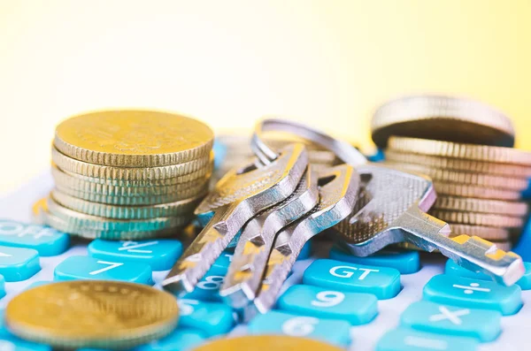 Укладка монет и связки ключей на калькуляторе на деревянном столе для концепции ипотечных кредитов — стоковое фото