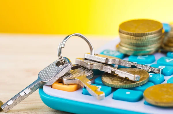 Empilant des pièces et un tas de clé sur la calculatrice sur fond de bureau en bois pour le concept de prêts à domicile — Photo