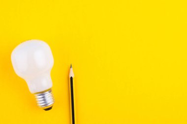 yaratıcı fikirler kavramı için sarı arka plan üzerinde kalem ve ampul