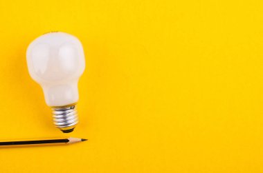 yaratıcı fikirler kavramı için sarı arka plan üzerinde kalem ve ampul