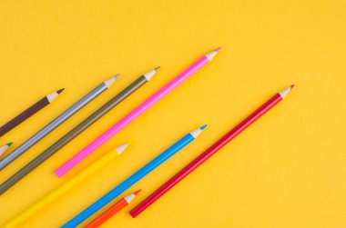 Sarı arka plan üzerinde renkli kalemlerin yakın çekim görüntüsü