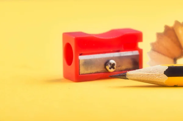 Blyertspenna med det spån och vässare över gul bakgrund — Stockfoto